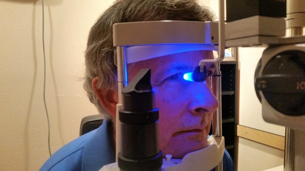 Active babyboomer at the doctors office for annual eye exam with an eye pressure exam for glaucoma.